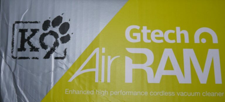 Product packaging for the Gtech AirRam K9 cordless vacuum cleaner features a K9 paw print logo and the words "Enhanced high performance cordless vacuum cleaner" in white and yellow—perfect for those seeking a top-rated vacuum cleaner after reading a review.