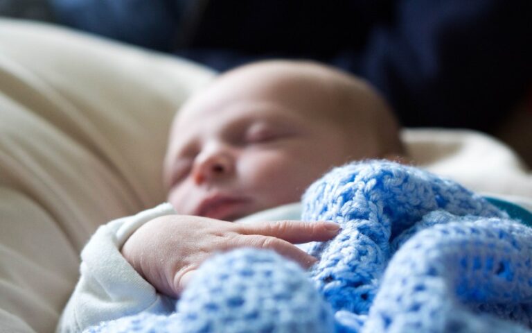A newborn baby sleeps peacefully, wrapped in a soft blue crocheted blanket, with their hand near their face. The softly blurred background adds to the serene atmosphere—a precious moment from our weekend in pictures, week 32.