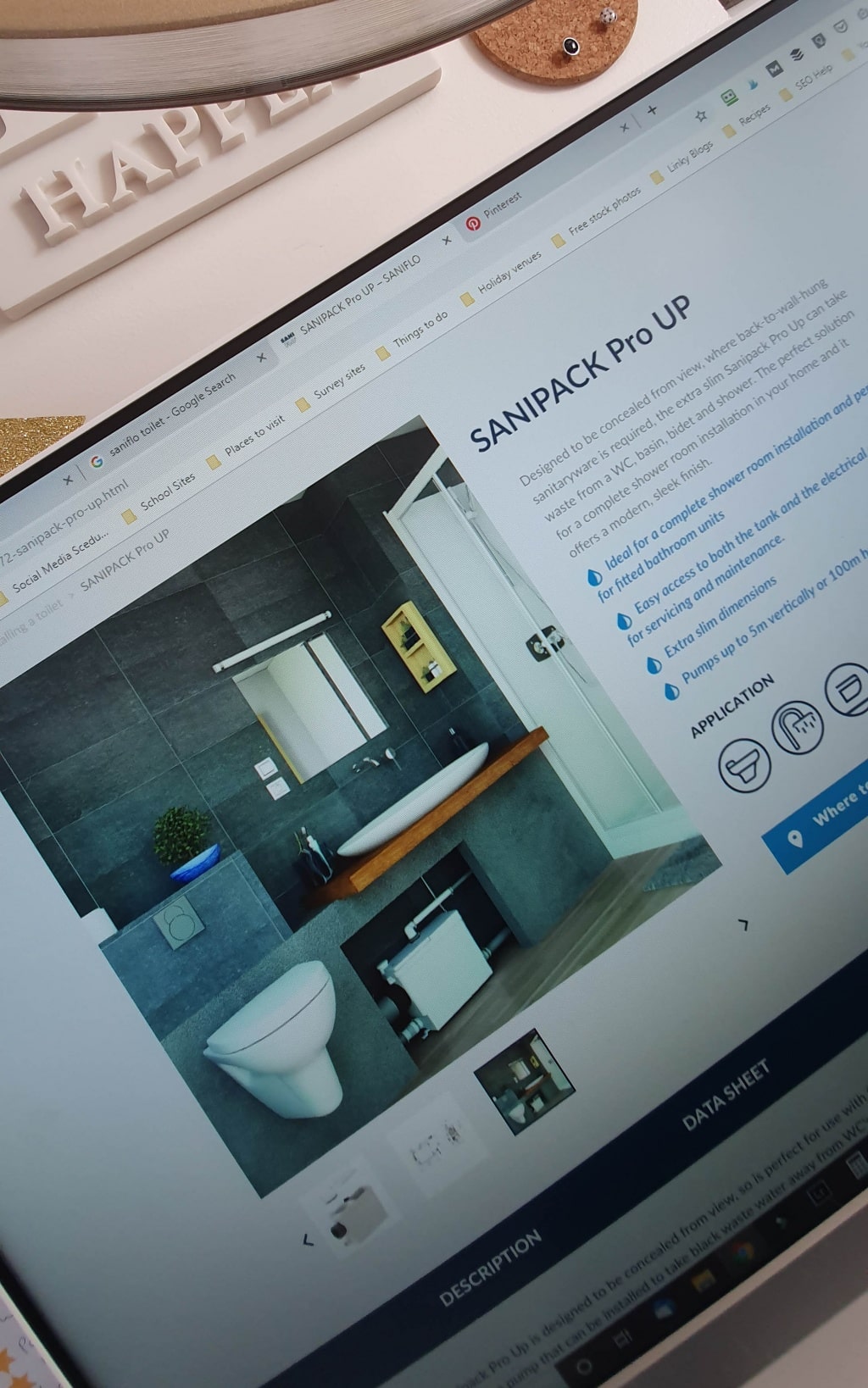 A computer screen displays a product page for the SANIPACK Pro UP, featuring a modern bathroom—ideal for home renovation projects—with a wall-mounted toilet, basin, mirror, grey tiled walls, product details, and navigation tabs.