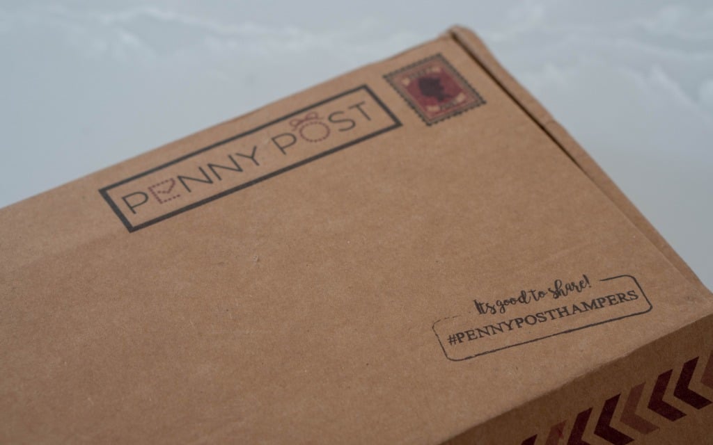 A brown cardboard box with Penny Post and a stamp printed on it. Perfect for Mother’s Day 2020, the box also features the text It’s good to share! #PENNYPOSTHAMPERS in the lower right corner—ideal for any gift guide.