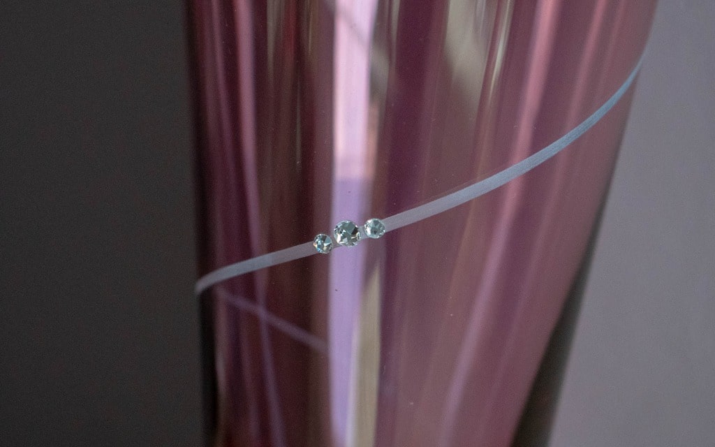 A close-up of a pink, reflective glass vase with a thin white diagonal stripe and three small, clear decorative gems—an elegant choice for any 2020 Mother’s Day gift guide.