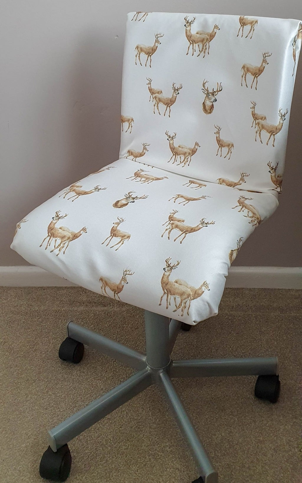 Office chair covered with fabric featuring a repeating pattern of brown deer, standing on a beige carpet next to a light-coloured wall—perfect for adding charm to your next Bedroom Tour or Small Bedroom Reveal.