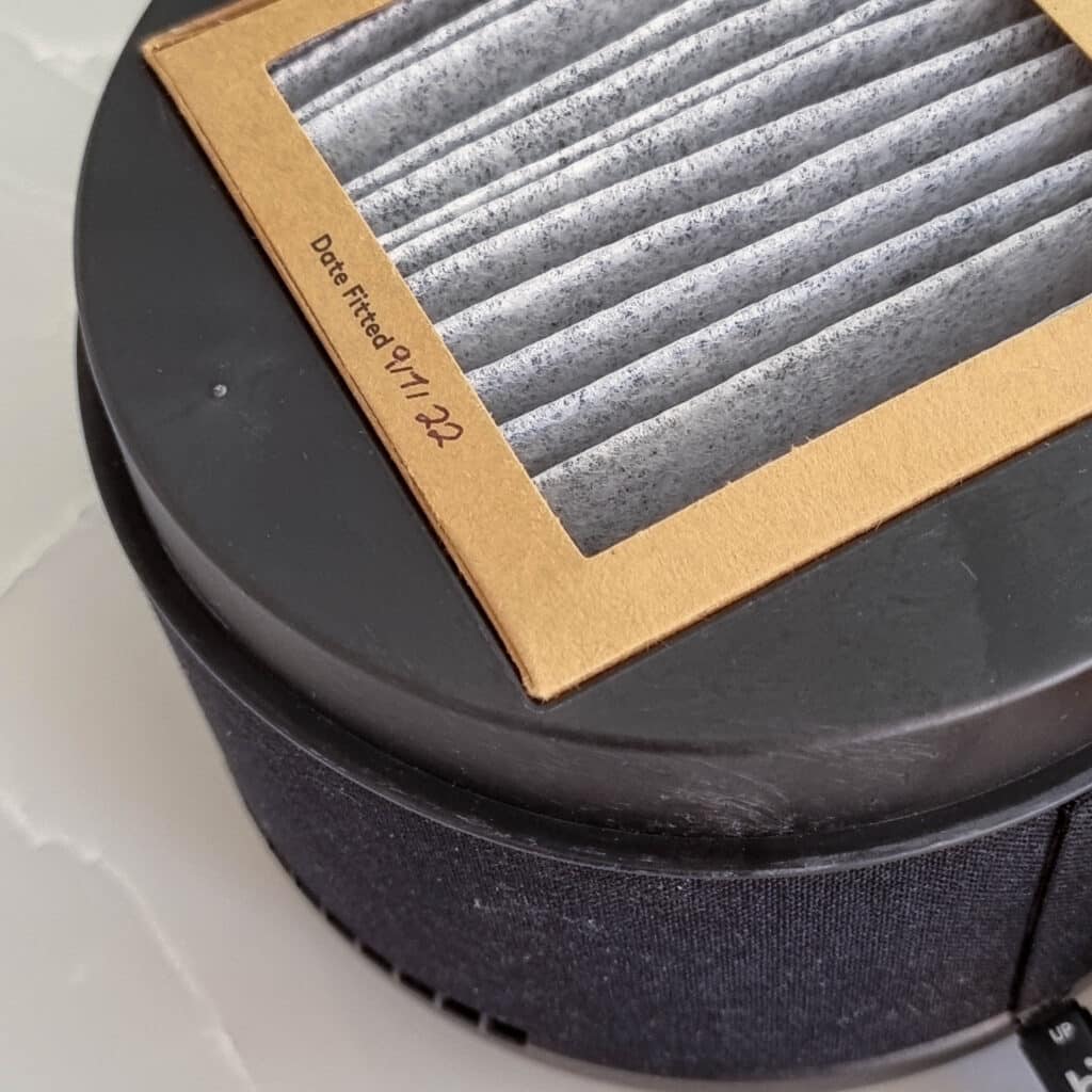 Close-up of a rectangular air filter with a cardboard frame labelled Date Fitted: 17/9/22, placed atop a round black appliance, possibly for a Briiv air purifier—a detail often noted in an air purifier review.
