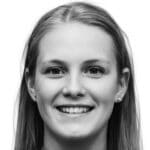 Black and white portrait of a young woman with straight, fair hair, smiling at the camera. She is wearing small stud earrings and has a friendly expression, ready to discuss your next basement refurbishment. The background is plain white.