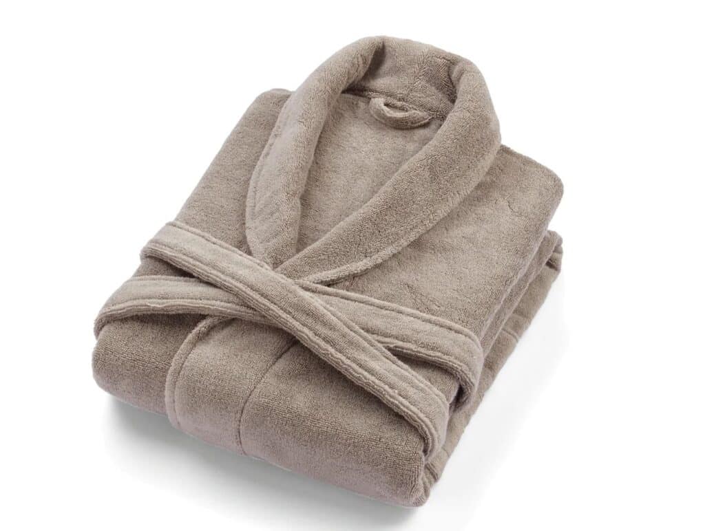 A folded, light brown dressing gown with a shawl collar and belt, neatly arranged on a white background—perfect for cosy autumn winter bedroom comfort.