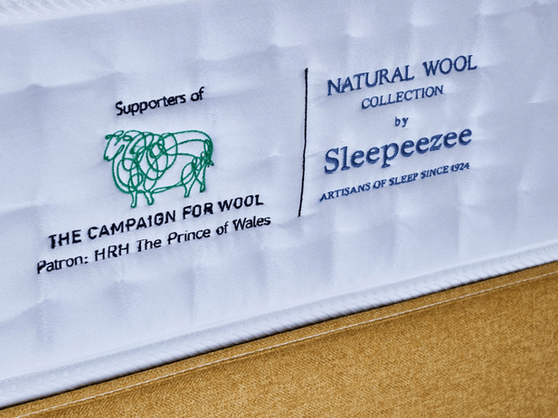Close-up of a mattress label showing logos and text: Supporters of The Campaign for Wool, Patron: HRH The Prince of Wales, and Natural Wool Collection by Sleepeezee—makers of the Best Beds for Summer since 1924.
