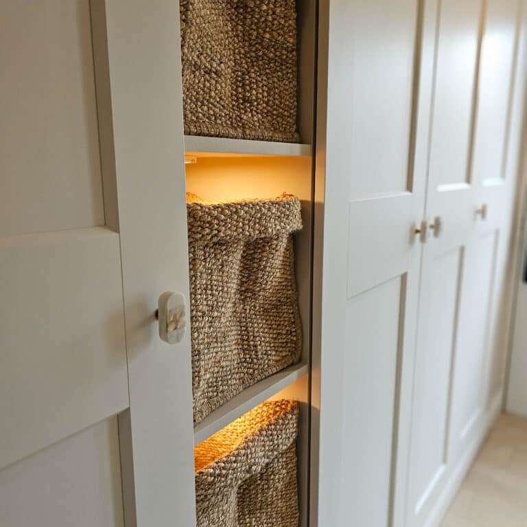 Baskets in a cupboard with white cabinets create organised storage, perfect for an IKEA Pax or as part of an Entranceway IKEA PAX Hack.