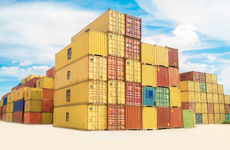 Stacks of colourful shipping containers are arranged outdoors under a bright blue sky with scattered clouds, their vibrant hues as eye-catching as the reasons why double glazed windows are popular for modern buildings.